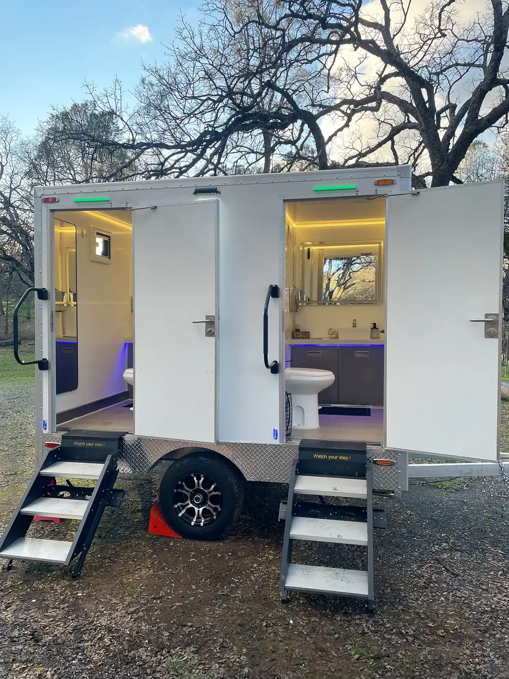 Two-door luxury restroom trailer with lit interior and folding steps