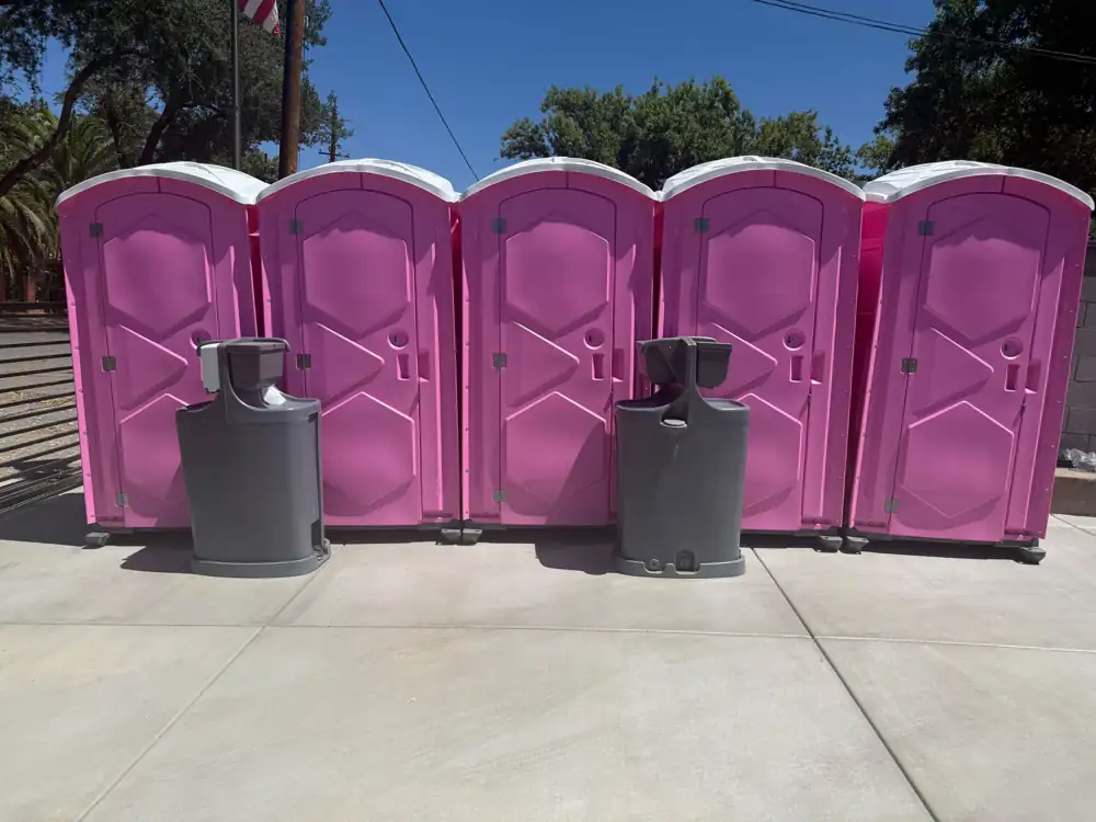 Pink porta potties with hand-wash stations at an event