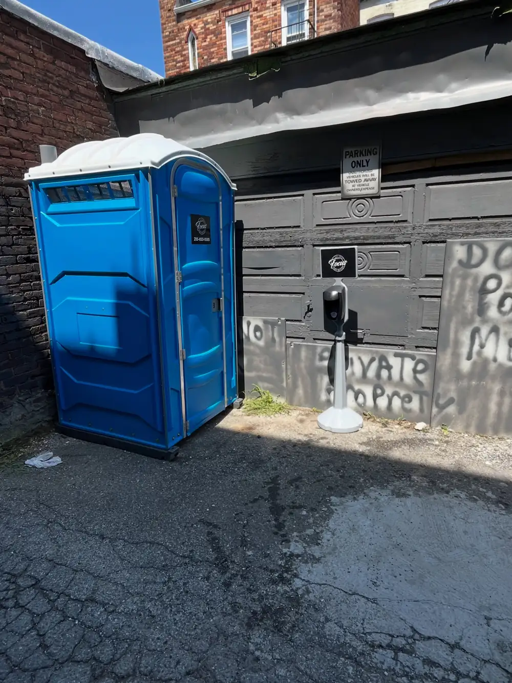 Blue porta potty set beside a driveway gate after same-day delivery