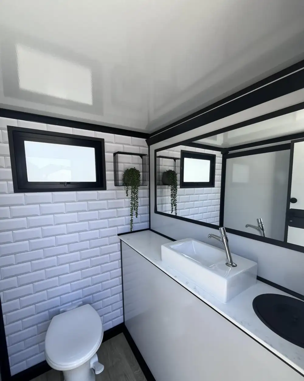 Restroom trailer interior with white tile, vanity sink and toilet
